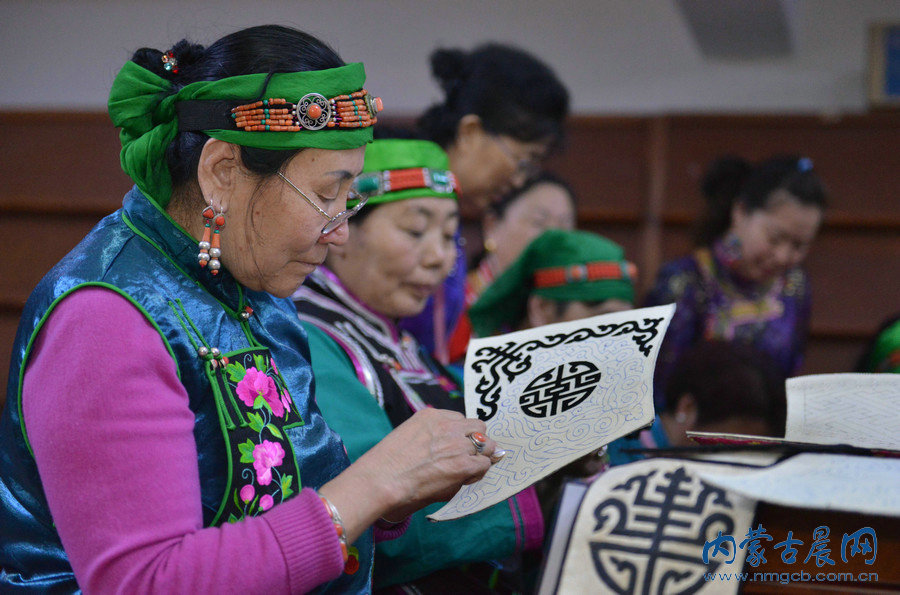 传承人集体展示哈斯琪琪格（前排中）创作的蒙古族刺绣巨幅作品《吉祥八宝》。