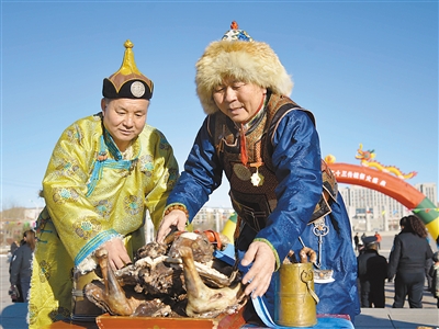 2月2日，身穿蒙古族服饰的牧民在内蒙古巴彦淖尔市乌拉特中旗祭火迎春仪式上摆放供品。